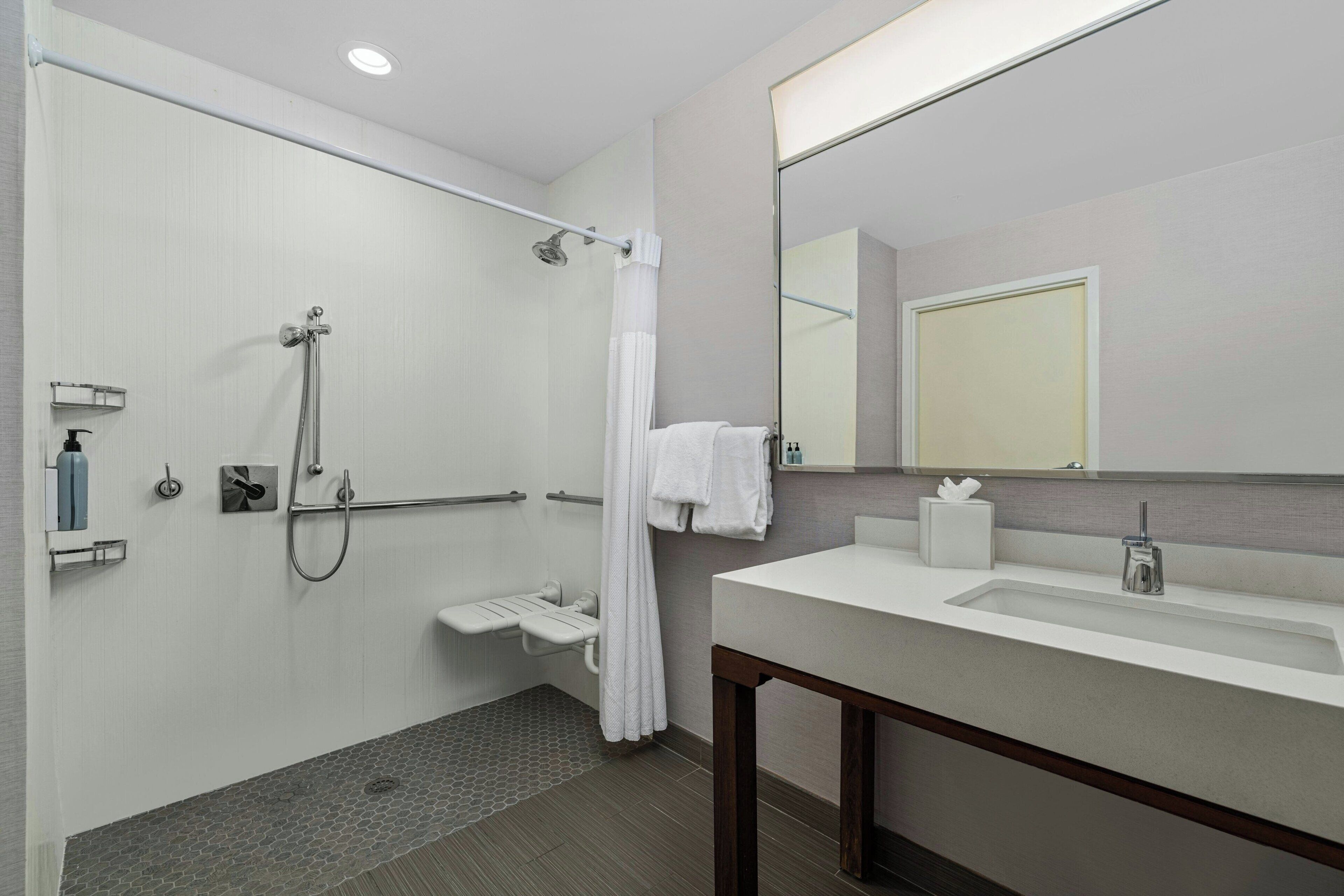 A modern bathroom with a shower, toilet, and sink.
