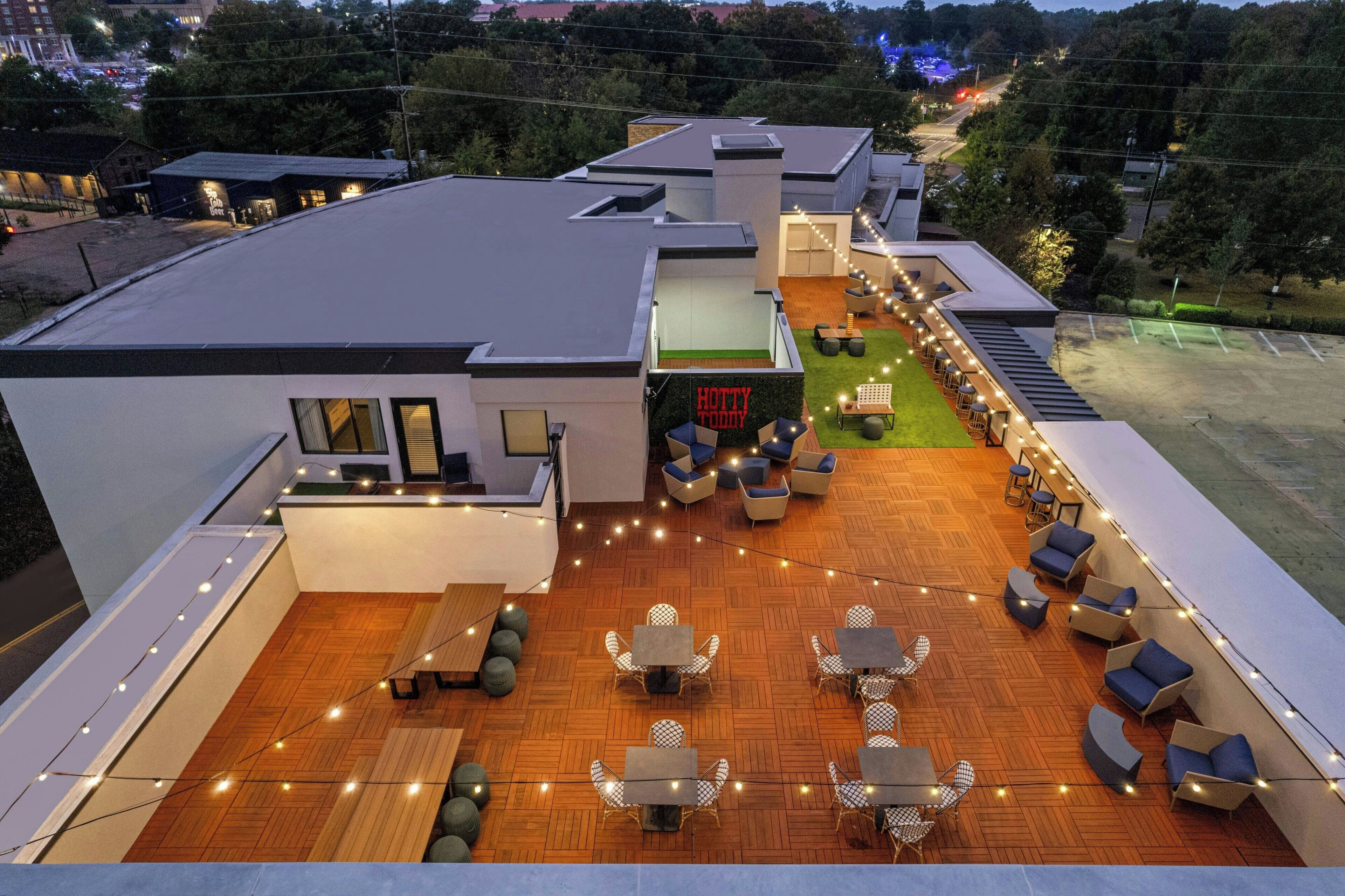 Un patio al aire libre con varios conjuntos de asientos y luces colgantes.