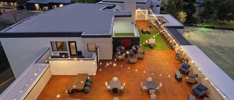 Un patio al aire libre con varios conjuntos de asientos y luces colgantes.
