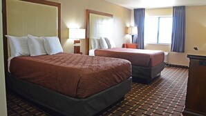 A hotel room with two beds, a large mirror, a desk, and a window with curtains. - Heritage Grand Inn (Canton)