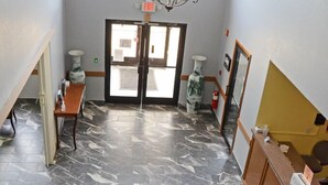 A hallway with a marble floor, a reception desk, a chandelier, and a door leading to another room. - Heritage Grand Inn (Canton)