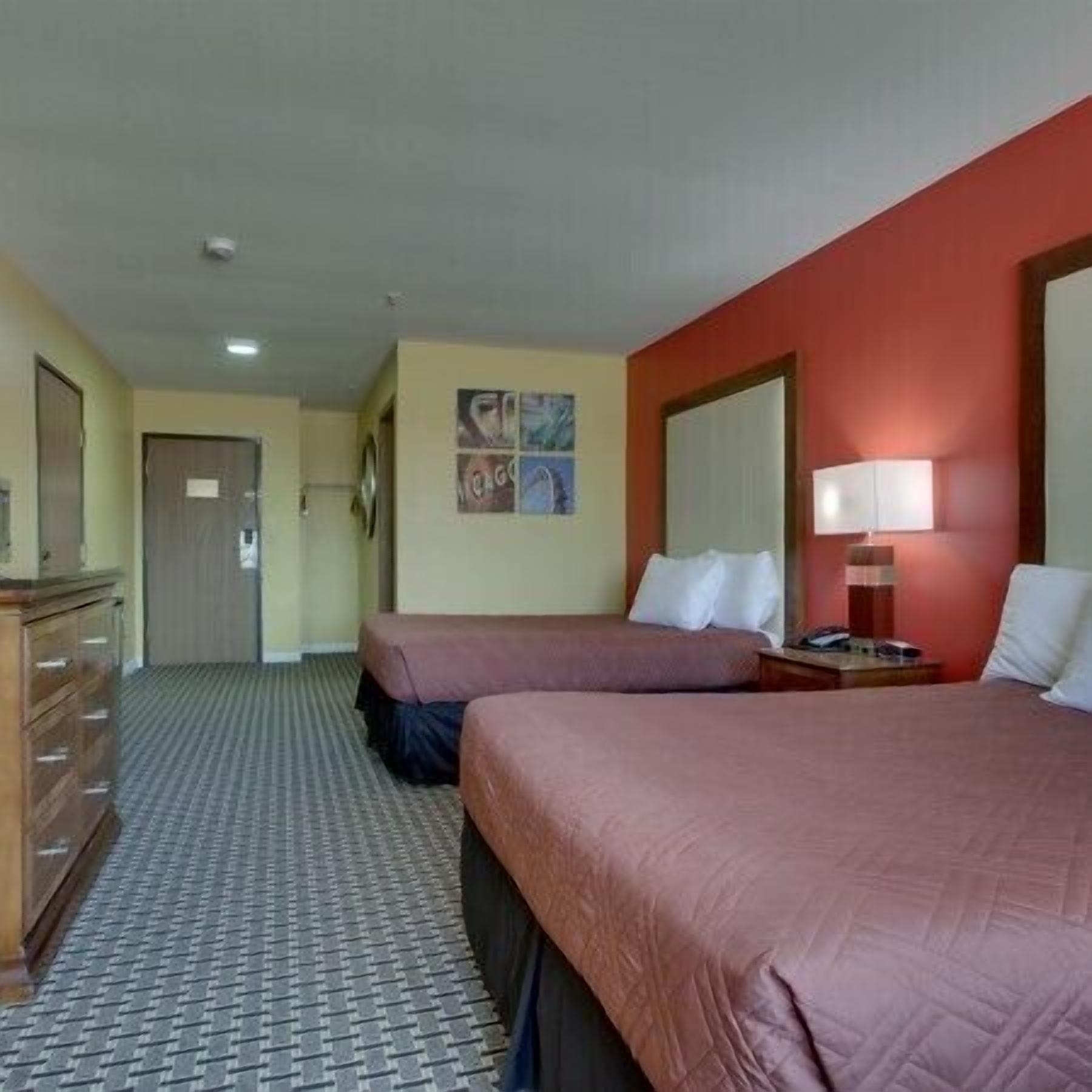 Habitación de hotel con dos camas, un aparador, una lámpara y una puerta.