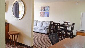 A room with a dining table, chairs, a sofa, a patterned floor, a mirror, and wall art. - Heritage Grand Inn (Canton)