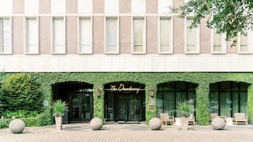 A building with a green ivy-covered facade, a sign reading "The Dewberry," and outdoor seating with planters.