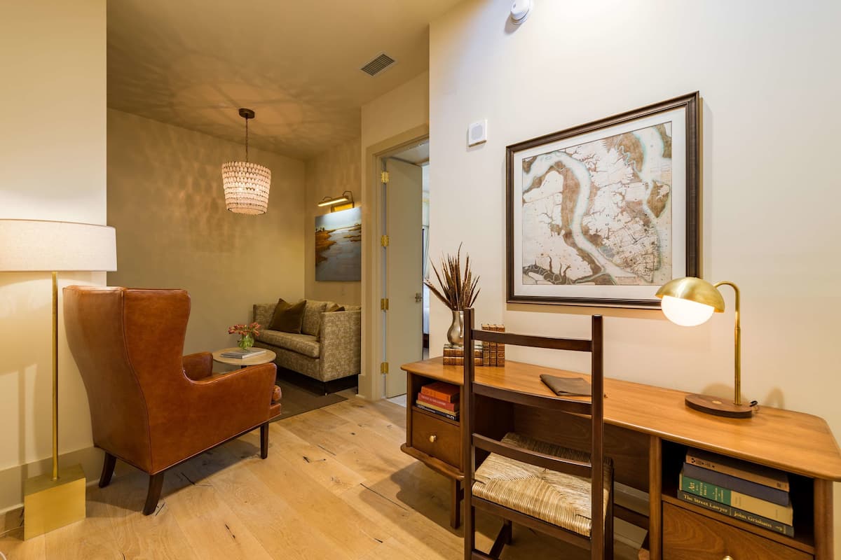 Un salon moderne avec un fauteuil en cuir, un bureau en bois et une œuvre d’art représentant une carte accrochée au mur.