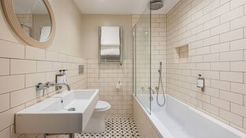 A modern bathroom with two sinks, a toilet, a shower, and a glass-enclosed shower area.