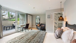 Une chambre avec un grand lit, un bureau et une chaise. Une porte-fenêtre coulissante donne accès à un espace extérieur.