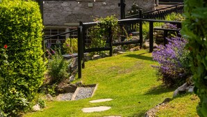 Un bâtiment en pierre avec un sentier de jardin qui mène à une clôture en bois.