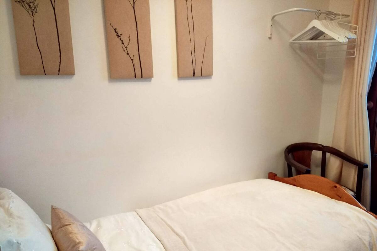 A bedroom with a bed, a chair, and three wall-mounted paintings.