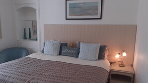 Un dormitorio ordenado con cama, mesita de noche y un cuadro enmarcado en la pared.
