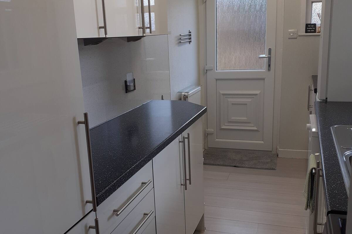 A kitchen with white cabinets, a black countertop, and a door with frosted glass.