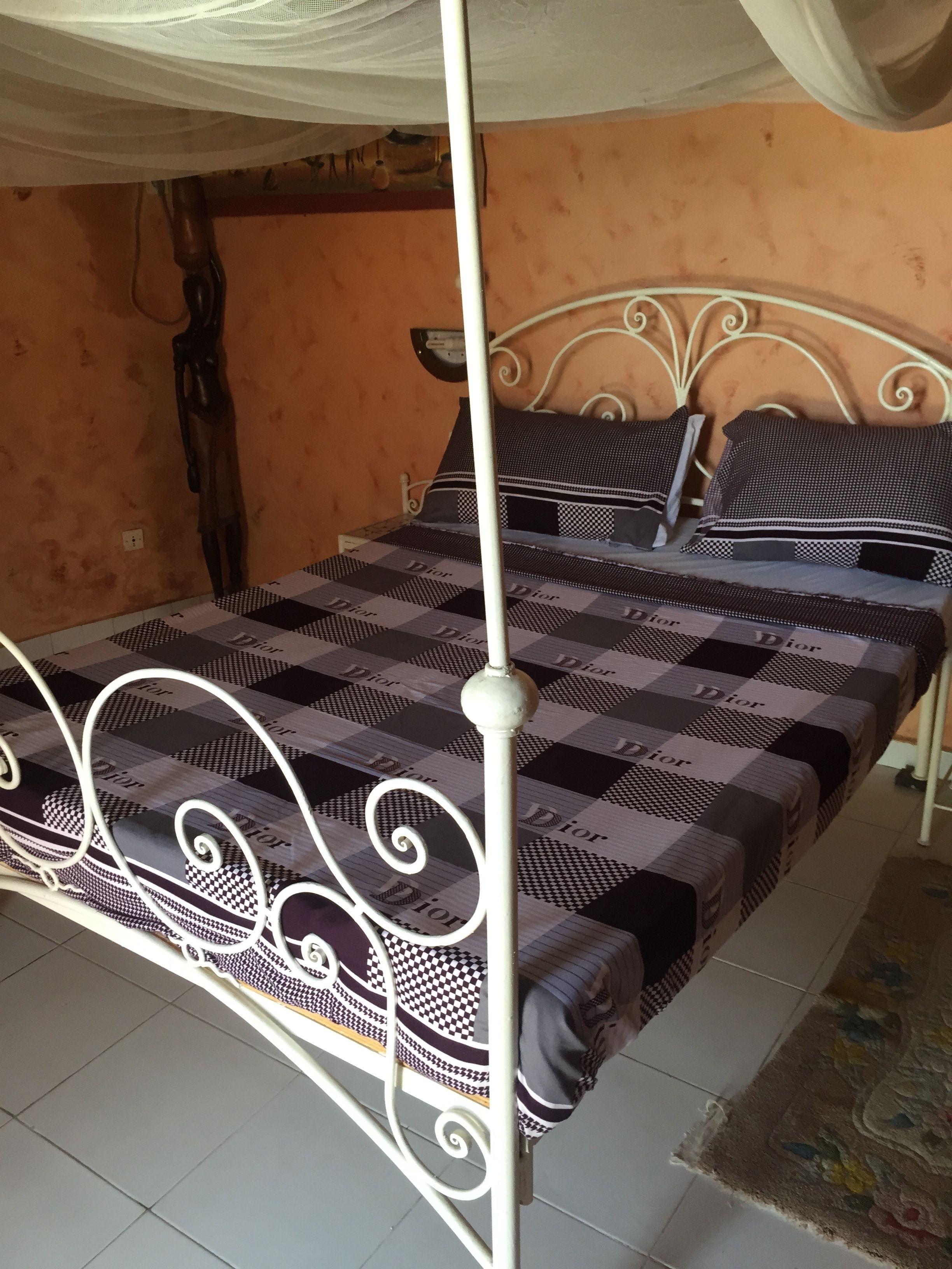 A bed with a checkered bedspread, white metal frame, and a canopy.