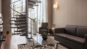 A modern living room with a spiral staircase, a leather sofa, a coffee table, and a potted plant.