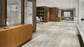Ein moderner Empfangsbereich mit einem Holzbüro, einer Sitzecke inklusive Sofa und Stühlen sowie einem großen abstrakten Gemälde an der Wand.