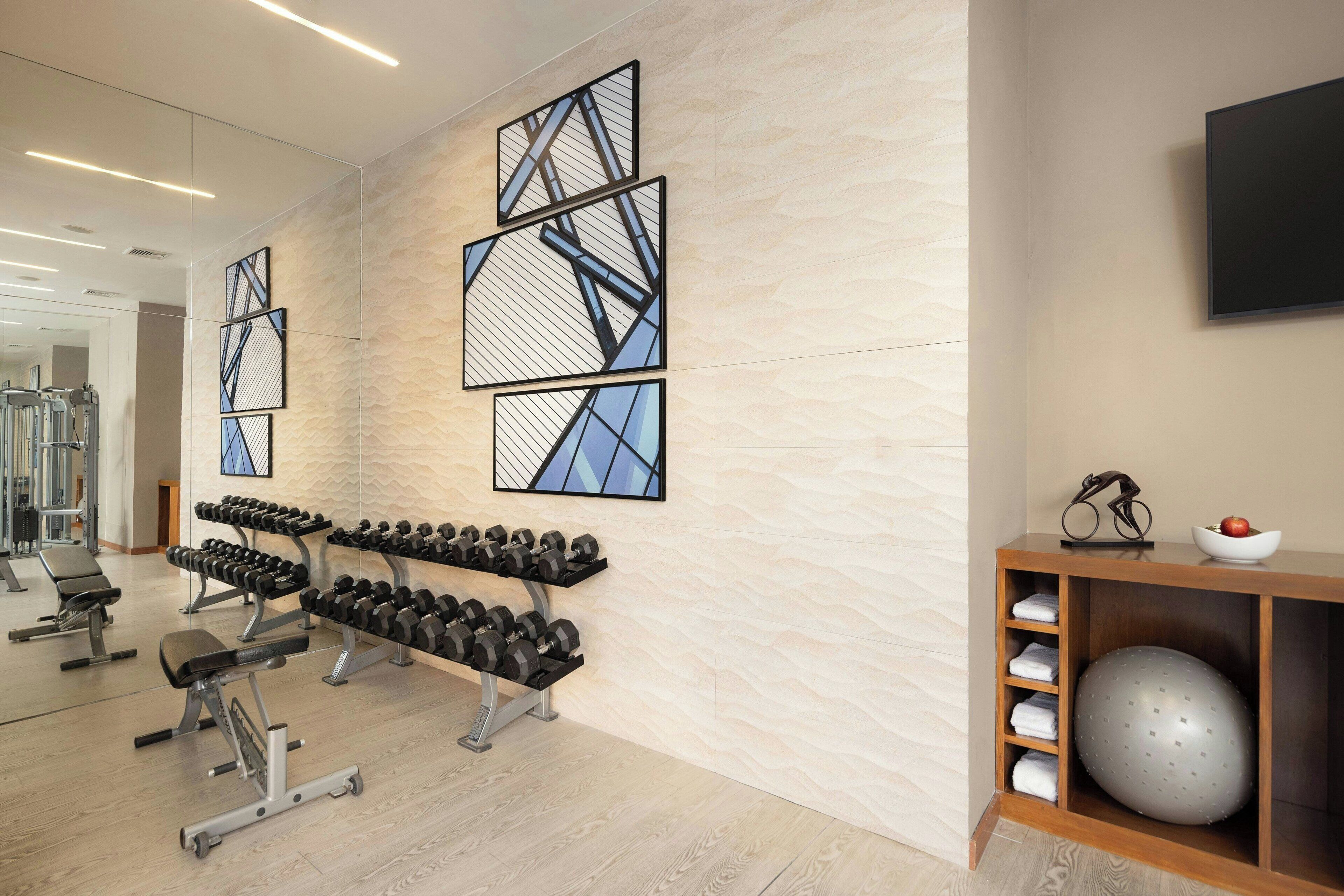 Een sportschool met trainingsapparatuur, kunst aan de muur en een televisie.
