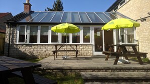 A building with a stone facade, large windows, and a covered patio area with two yellow umbrellas. - YHA Helmsley - Hostel (York)