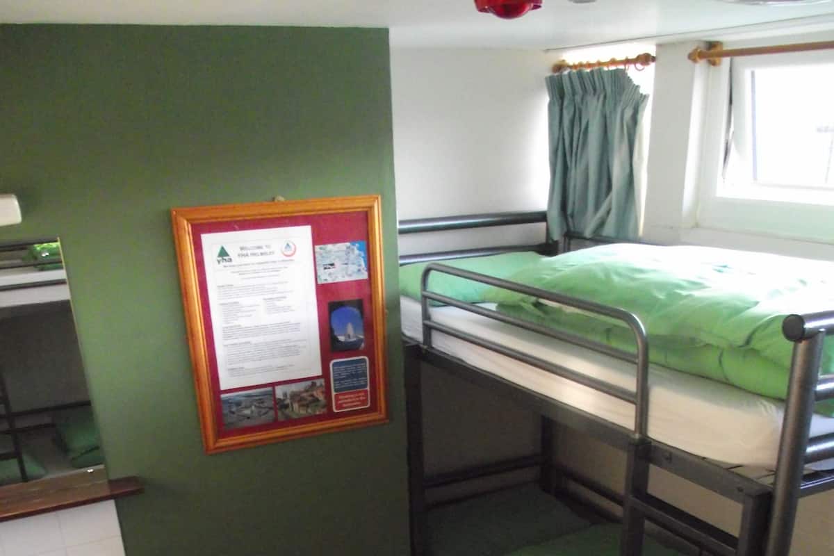 A bunk bed room with a sink and a small stool.