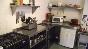 A compact kitchen with a gas stove, oven, microwave, and a small refrigerator. - YHA Helmsley - Hostel (York)