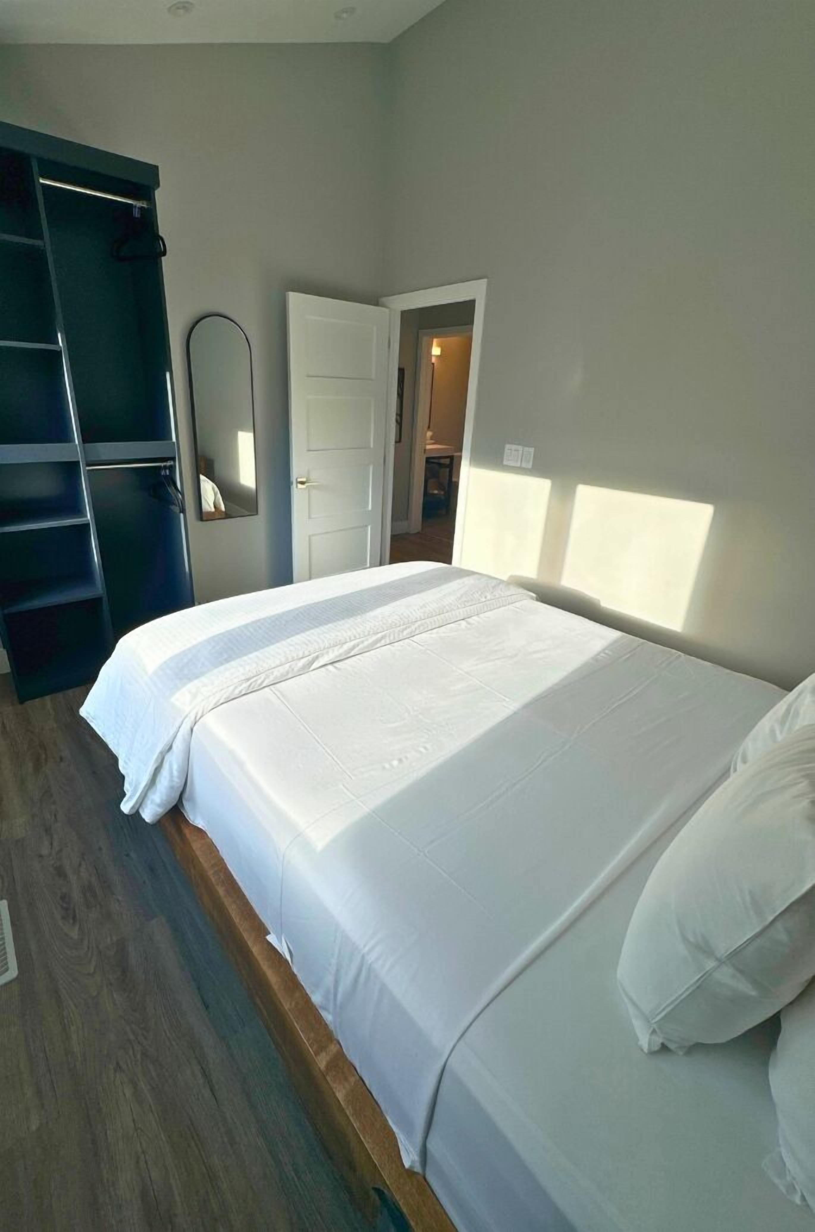 Un dormitorio con una cama, un armario y un espejo.