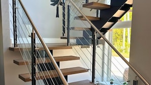 A modern staircase with glass railings and wooden steps. - Orchard Run Chalet (The Blue Mountains)