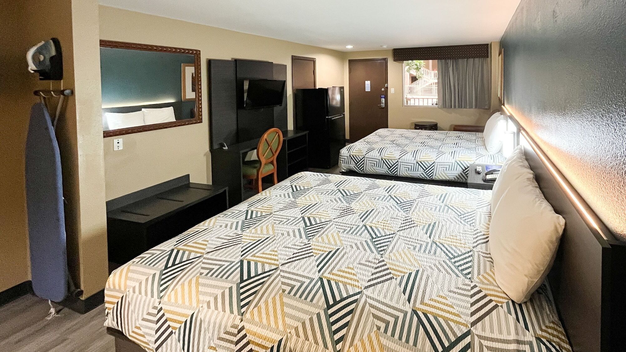A hotel room with two beds, a TV, a desk, and a chair.