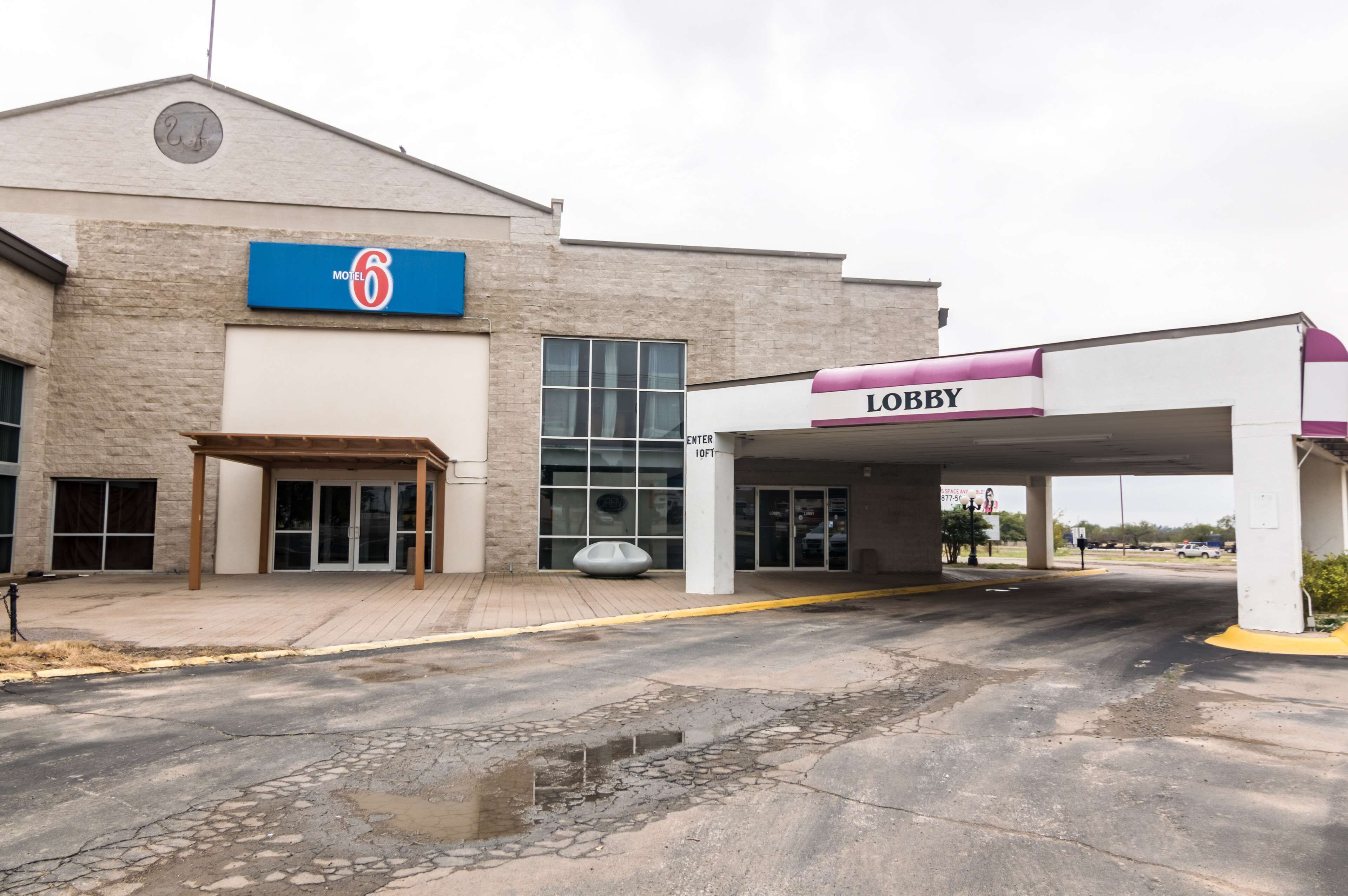 A motel with a '6' sign, a lobby entrance, and a parking area.