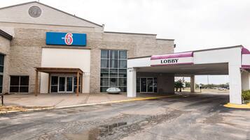 A motel with a '6' sign, a lobby entrance, and a parking area.