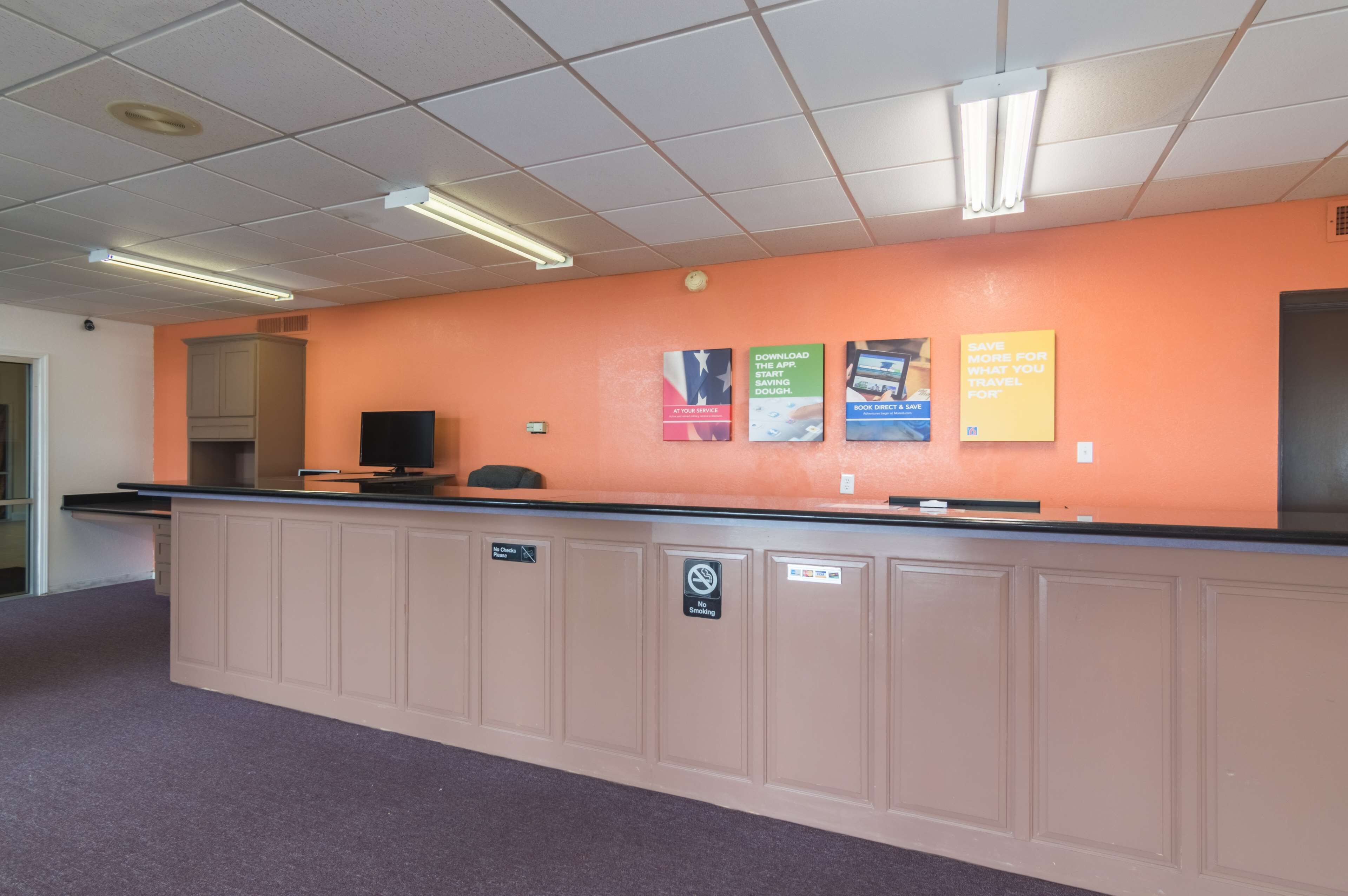 A reception desk with a computer, a no-smoking sign, and promotional posters on the wall.