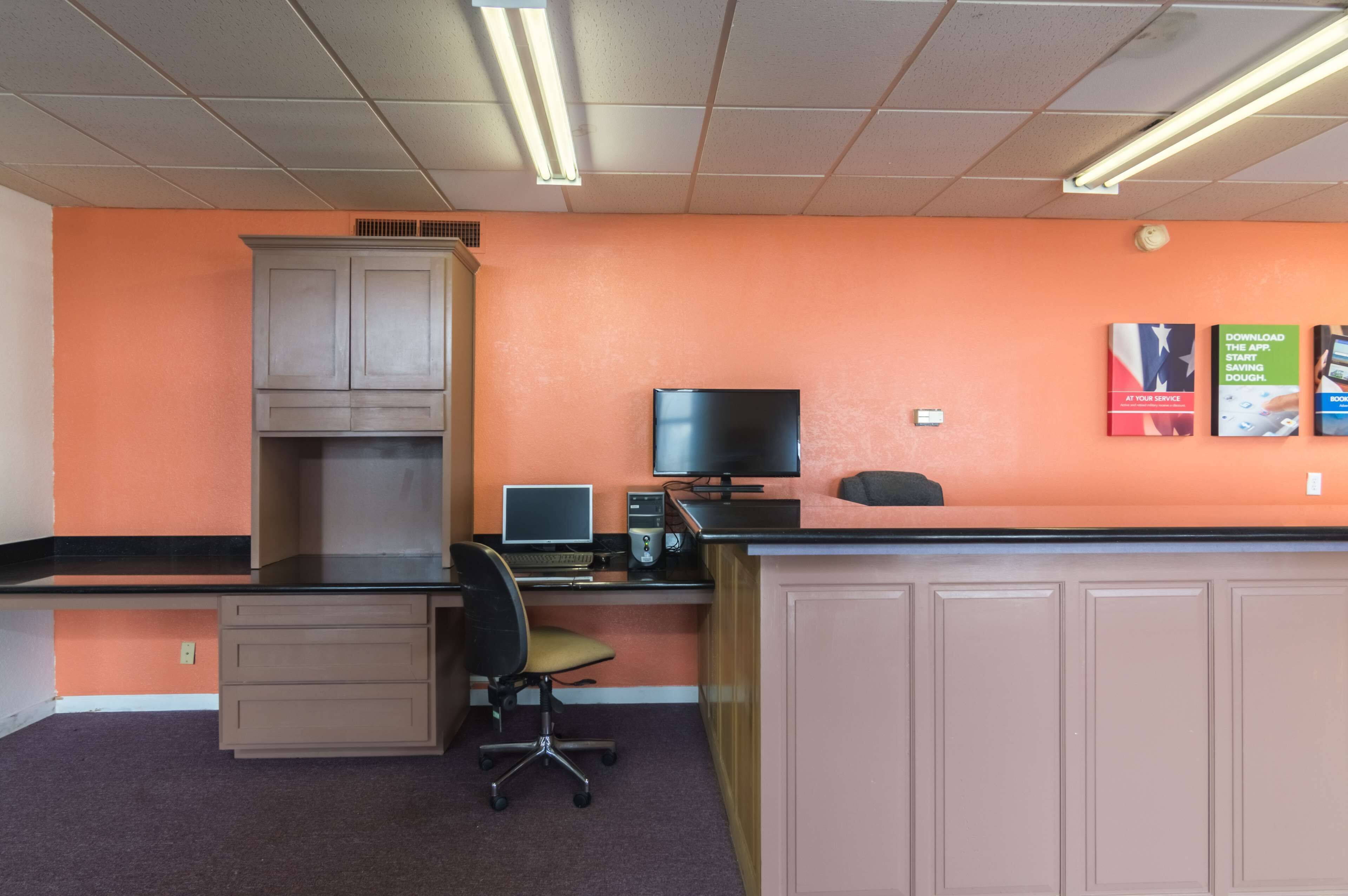 Una recepció amb un ordinador, una cadira i un armari.