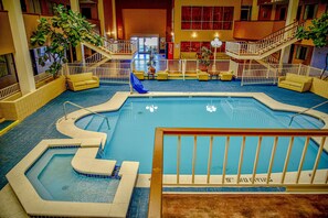 Una piscina interior con varios niveles, zonas de estar y un letrero de Coca-Cola.