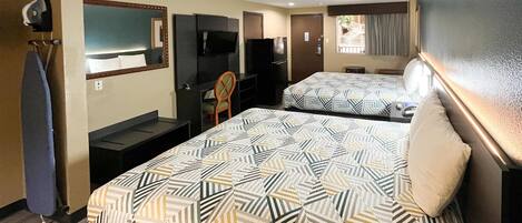 A hotel room with two beds, a TV, a desk, and a chair.