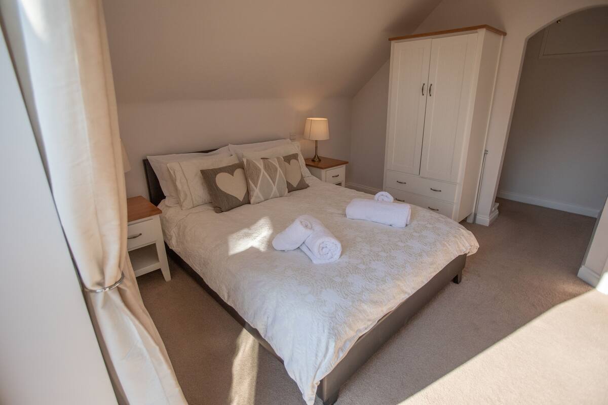 A bedroom with a bed, nightstands, a wardrobe, and a lamp.