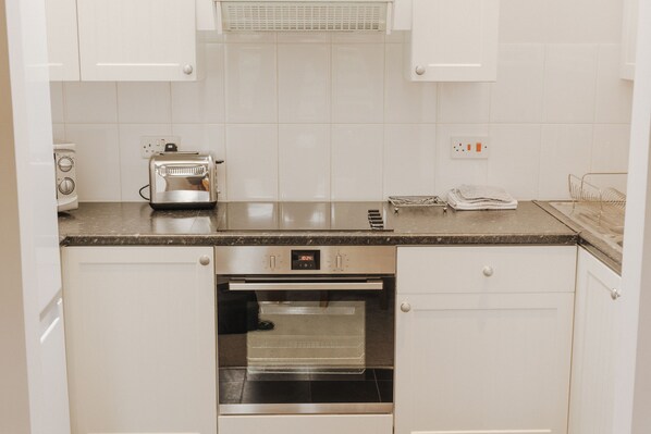 A kitchen with white cabinets, a stainless steel oven, a toaster, and a microwave. - Newclose Farm (Yarmouth)