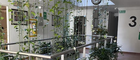 A modern indoor space with a metal staircase, potted plants, and a tiled floor.
