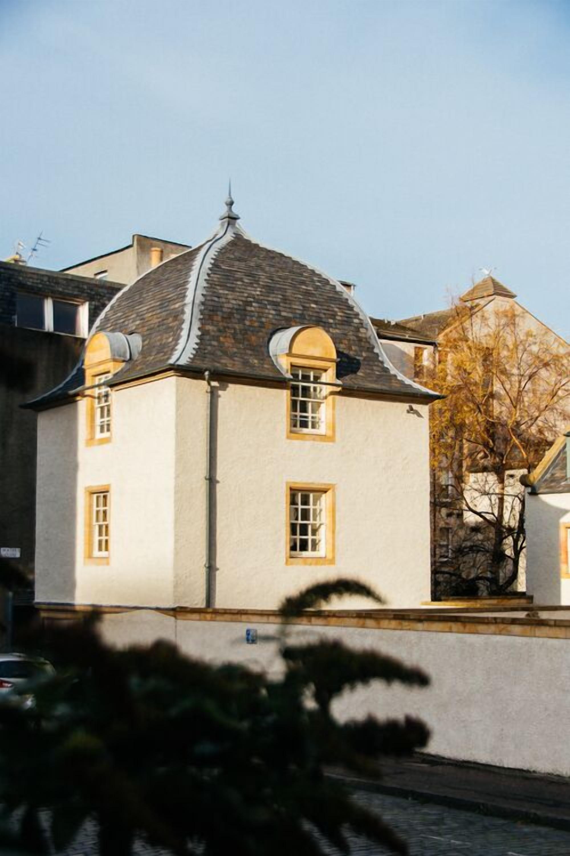 Un bâtiment à deux étages, doté d’un toit à pignon et d’une petite structure en forme de tour sur le toit.