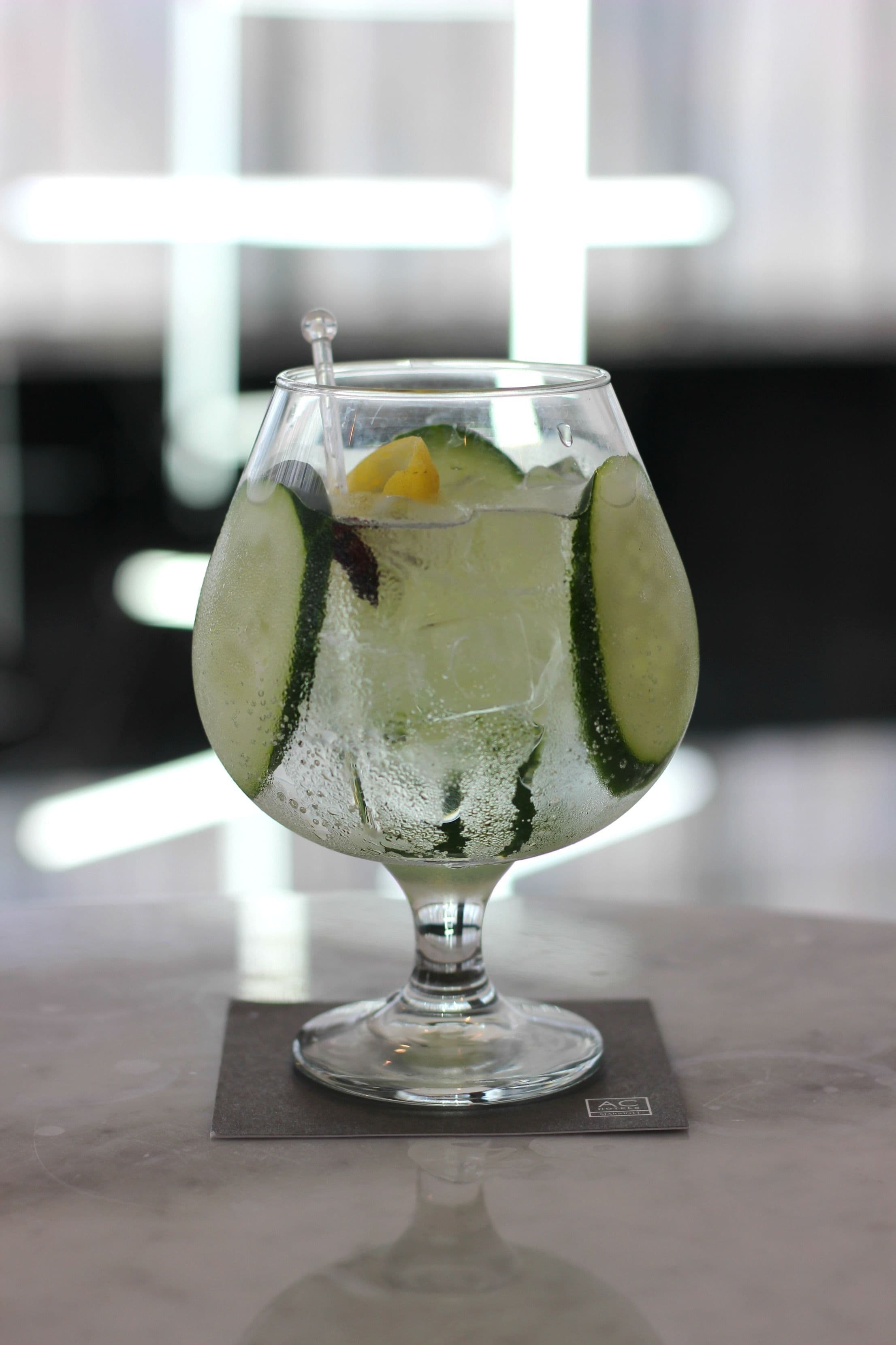 Un verre transparent contenant un quartier de citron vert et quelques feuilles de menthe, posé sur un dessous de verre foncé.