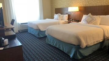 A hotel room with two beds, a desk, a telephone, and a lamp.