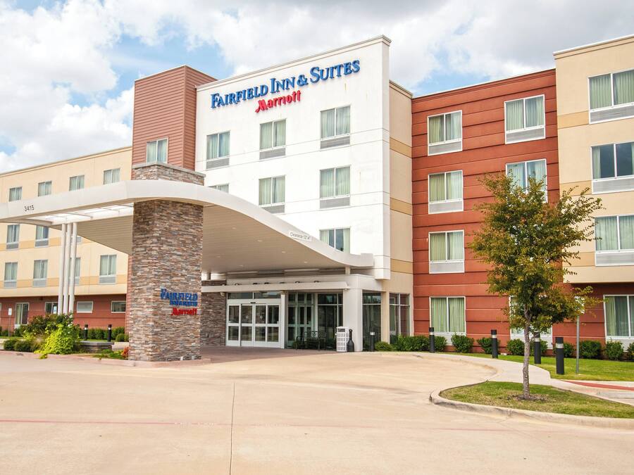 Ein Hotel Fairfield Inn & Suites Marriott mit modernem Design, das einen überdachten Eingang und mehrere Etagen aufweist.