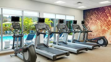 Gimnasio con cintas de correr, bicicletas estáticas y una zona de piscina visibles a través de amplios ventanales.