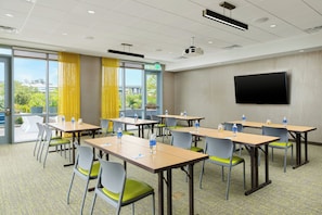 A conference room with tables, chairs, a projector, and a TV screen. - Springhill Suites San Diego Mission Valley (San Diego)