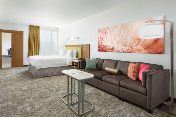 A hotel room with a bed, a sofa, a small table, and a large abstract painting on the wall. - Springhill Suites San Diego Mission Valley (San Diego)