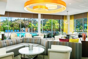 A modern lounge area with a pool view, comfortable seating, and a large window. - Springhill Suites San Diego Mission Valley (San Diego)