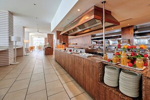 Ett modernt hotellkök med en buffé, inklusive ett varierat utbud av mat och köksredskap.