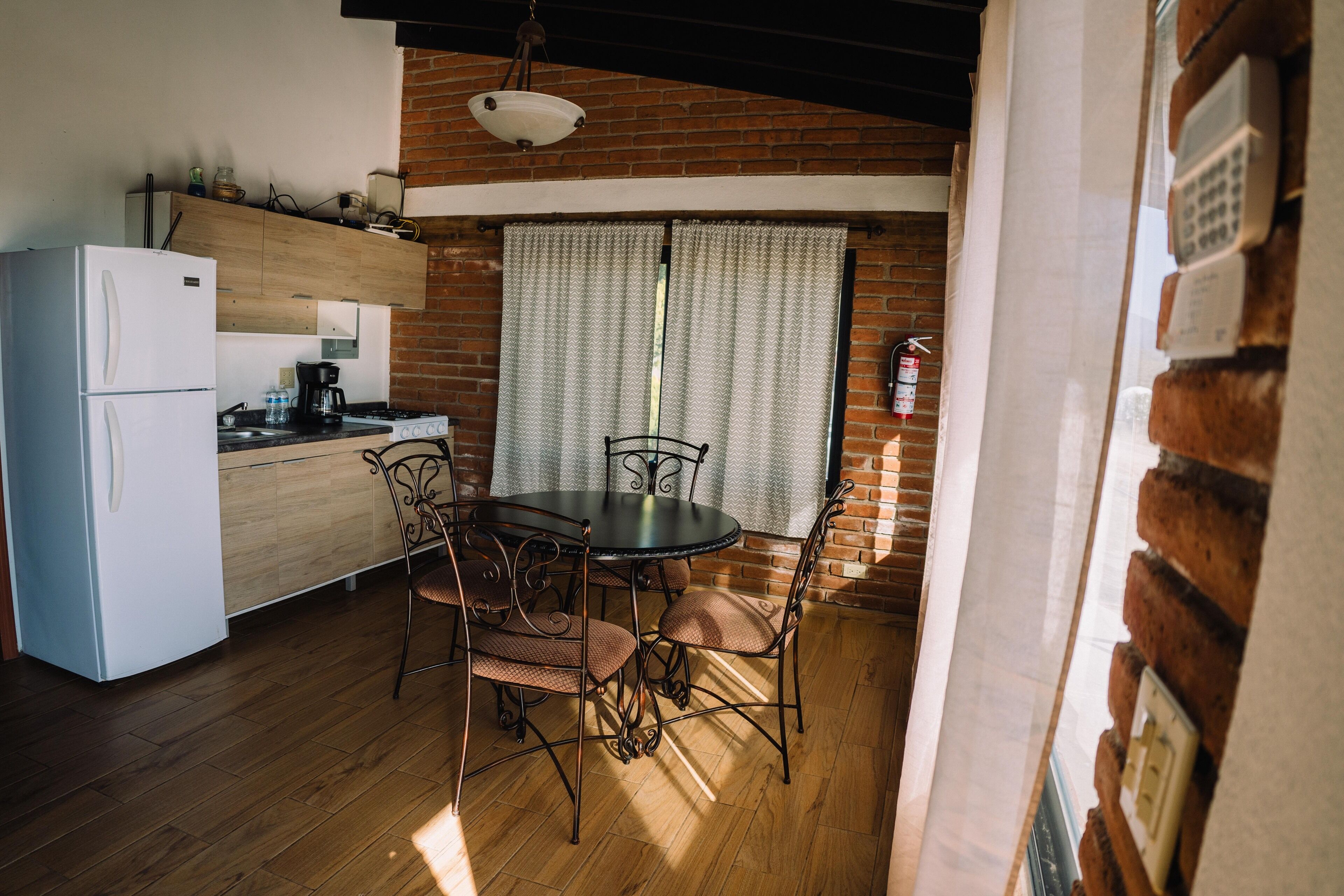 A kitchen with a refrigerator, stove, and dining table with chairs.