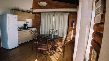 A kitchen with a refrigerator, stove, and dining table with chairs.