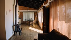 Una sala de estar acogedora con chimenea, un comedor con mesa y sillas, y una cocina visible a través de un umbral abierto.