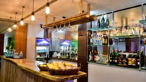 Una zona de bar con mostrador de madera, lámparas colgantes y estantes con botellas.
