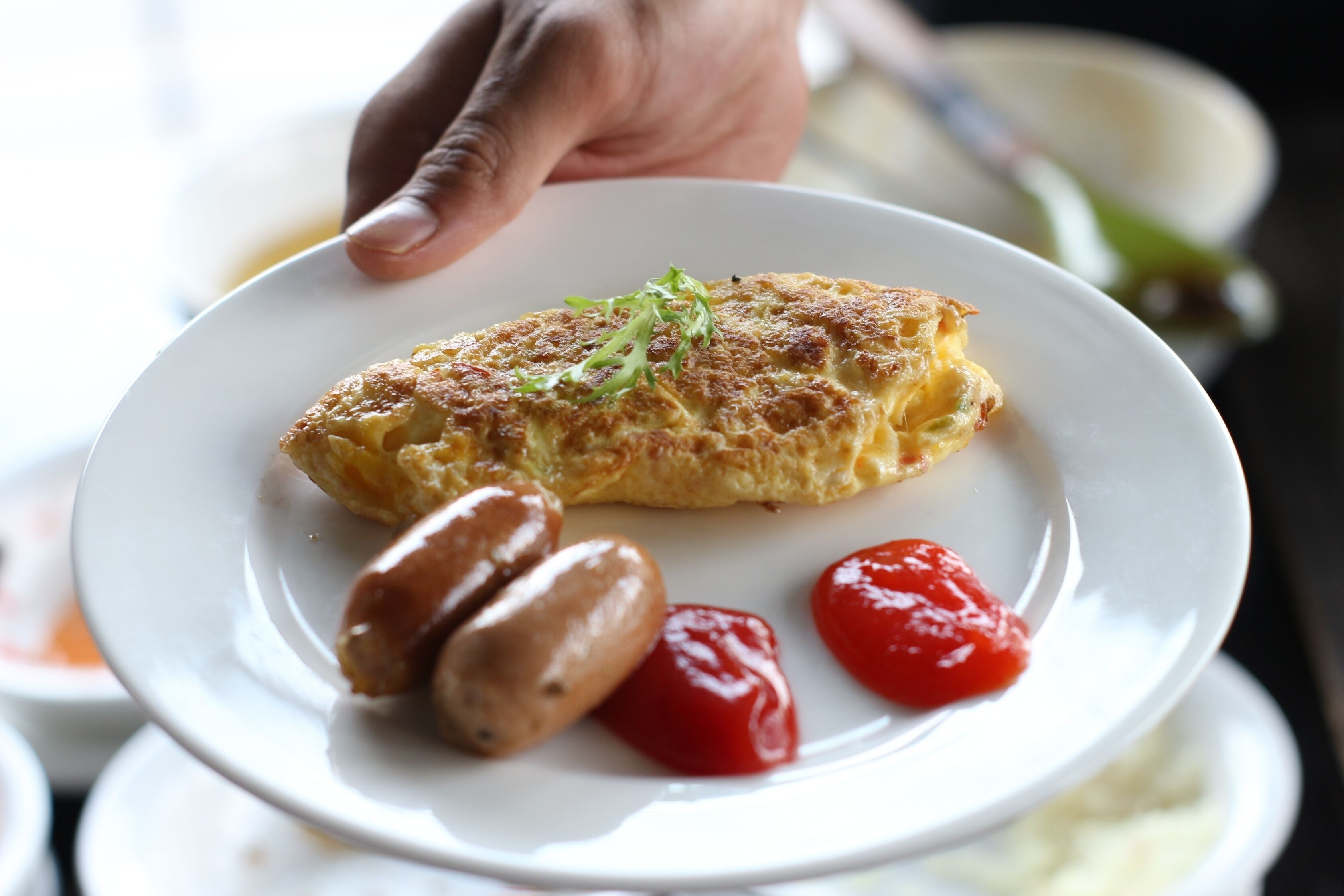 Ein Teller mit Omelett, Würstchen und Cocktailtomaten.