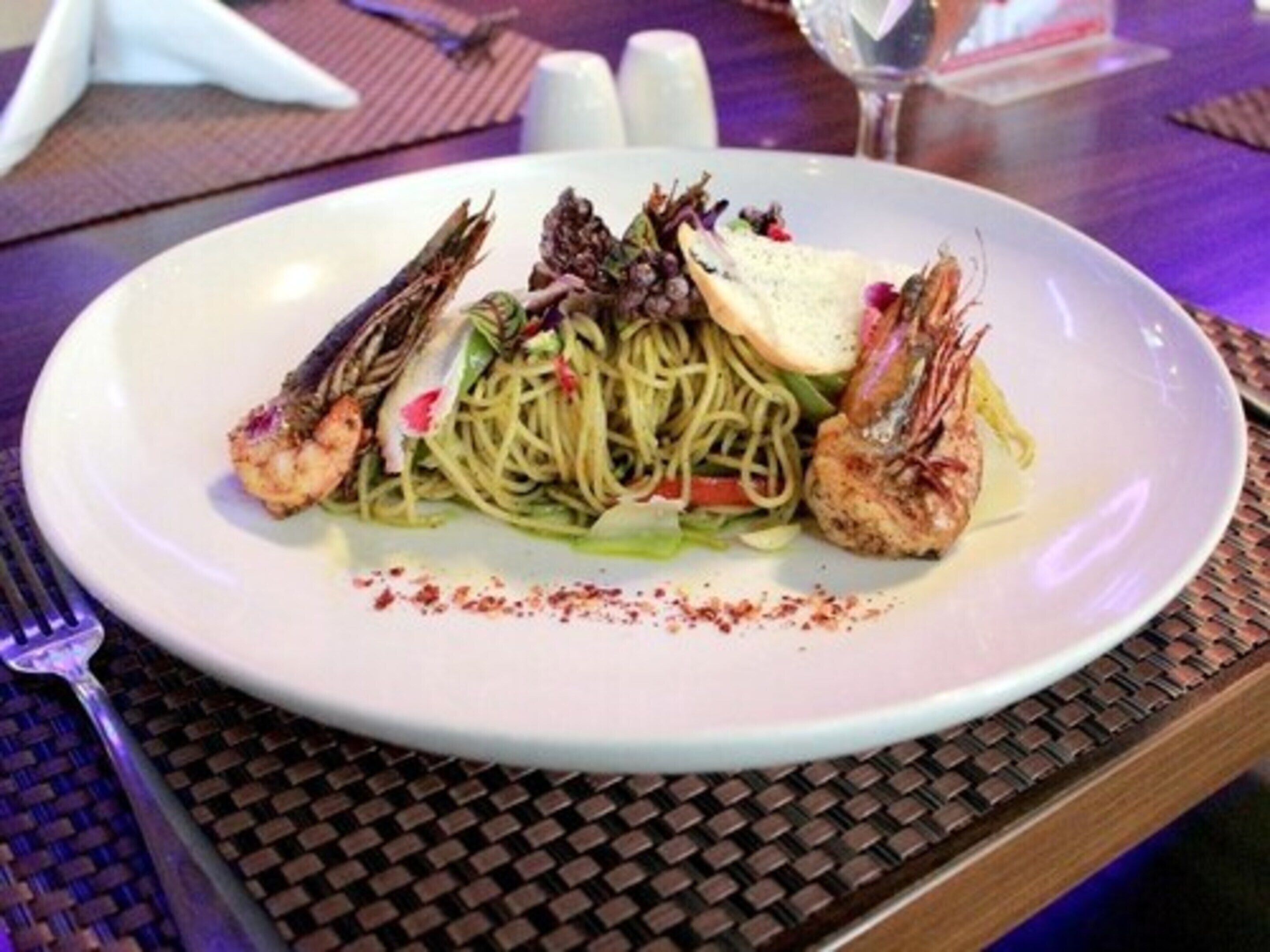 A plate of pasta with shrimp and a slice of bread on a white plate.
