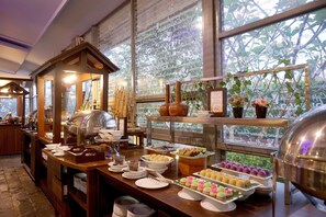 Un buffet proposant une variété de plats et une grande fenêtre donnant sur un paysage verdoyant.